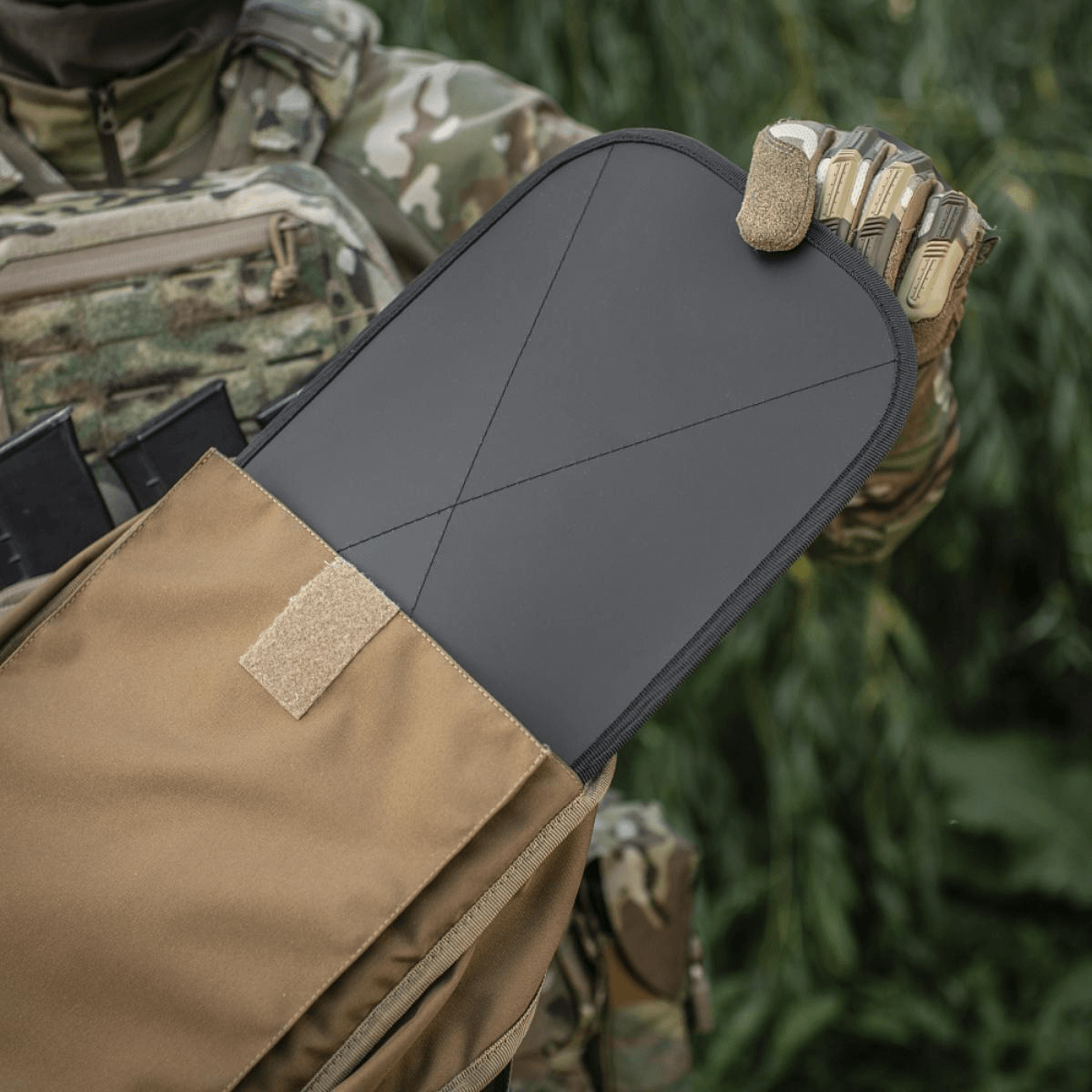 Soldat i camouflageuniform viser taktisk pladeholder med udtrukket beskyttelsesplade