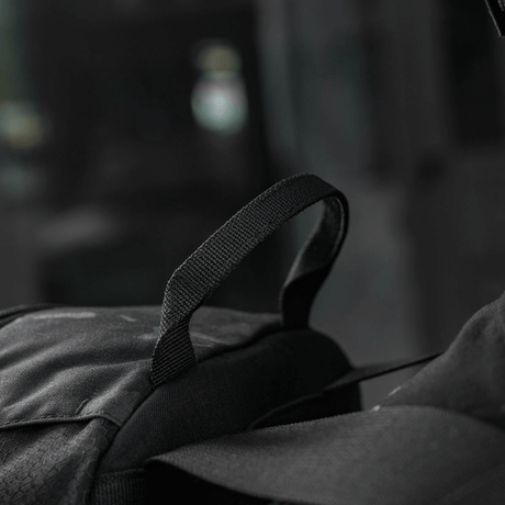 Sort rygsæk og strop i fokus med sløret baggrund