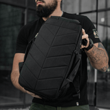 Mand viser sort rygsæk i moderne bymiljø