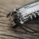 M-Tac Knife Lanyard Helix Skull på en lommekniv, der fremhæver det flettede paracord design og stil til hurtig adgang.