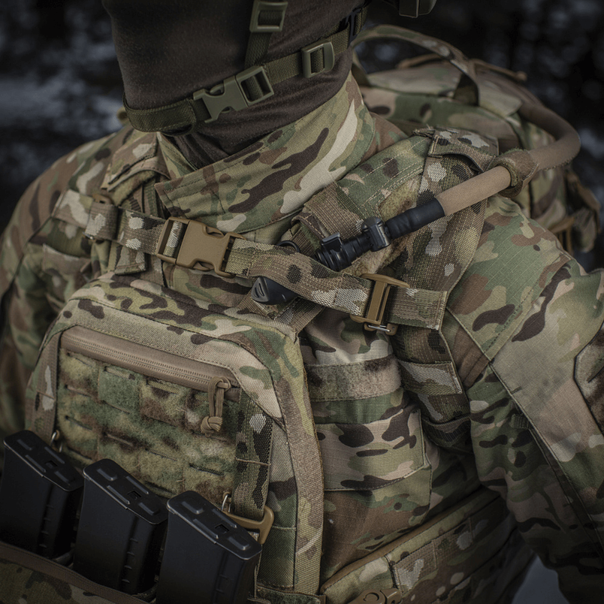 M-Tac Rygsæk Sturm Elite Gen.II i camouflagemønster med MOLLE system og indbygget drikkesystem, ses i en feltopsætning.
