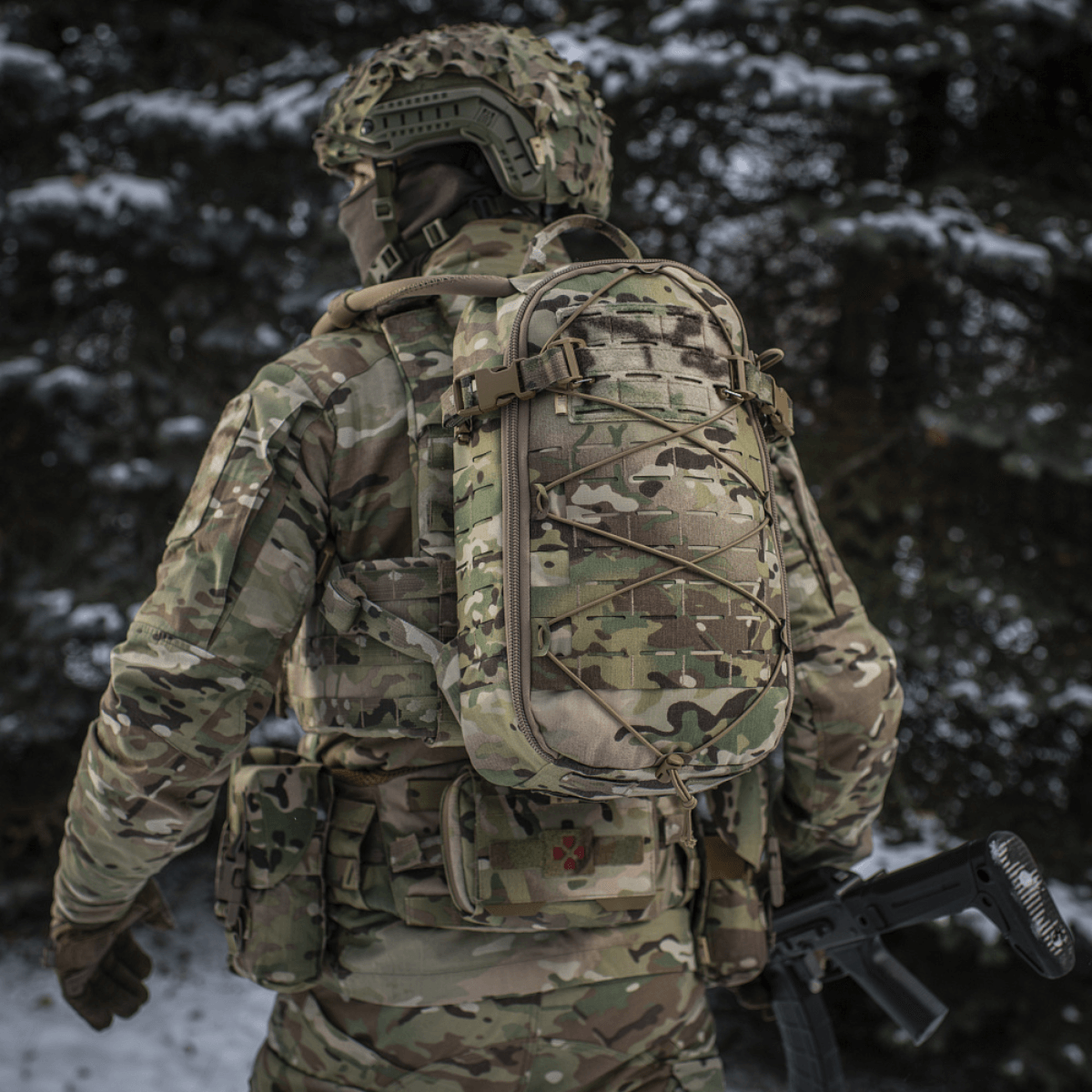 M-Tac Rygsæk Sturm Elite Gen.II i camouflagedesign med MOLLE system, set bagfra i skovmiljø med sne.