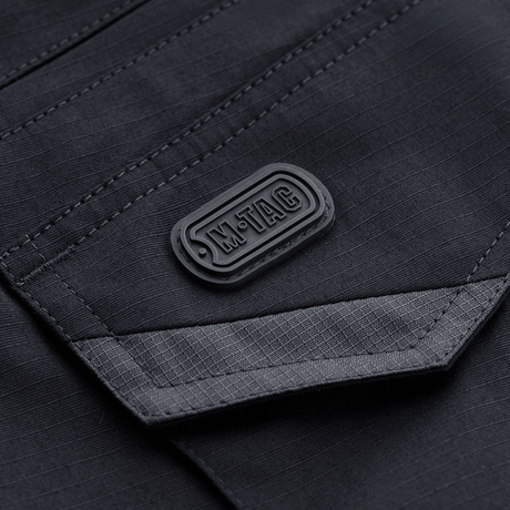 Detaljebillede af M-Tac Shorts Aggressor Gen.II Flex med M-Tac logo, lavet af rip-stop materiale med Teflon-belægning.
