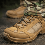 Nærbillede af taktiske støvler i læder og stof i brug på grusvej, ideelle til udendørs aktiviteter og barske forhold.