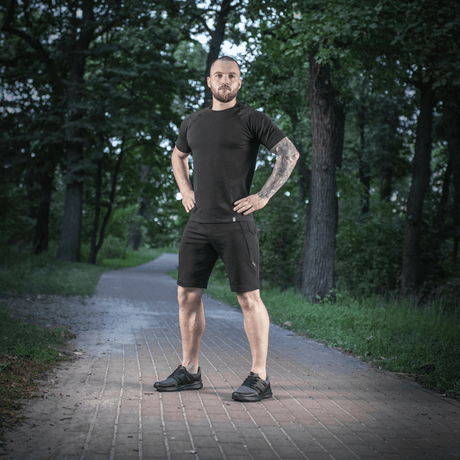 Mand iført M-Tac Shorts Casual Fit Cotton, står på en skovsti. Fokus på komfortabel pasform og stilrent sommerdesign.