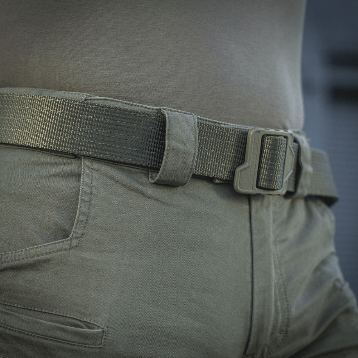 Nærbillede af M-Tac Bukser Patriot Gen.III Vintage med grøn bæltestrop, taktisk design og elastisk pasform, taget udendørs