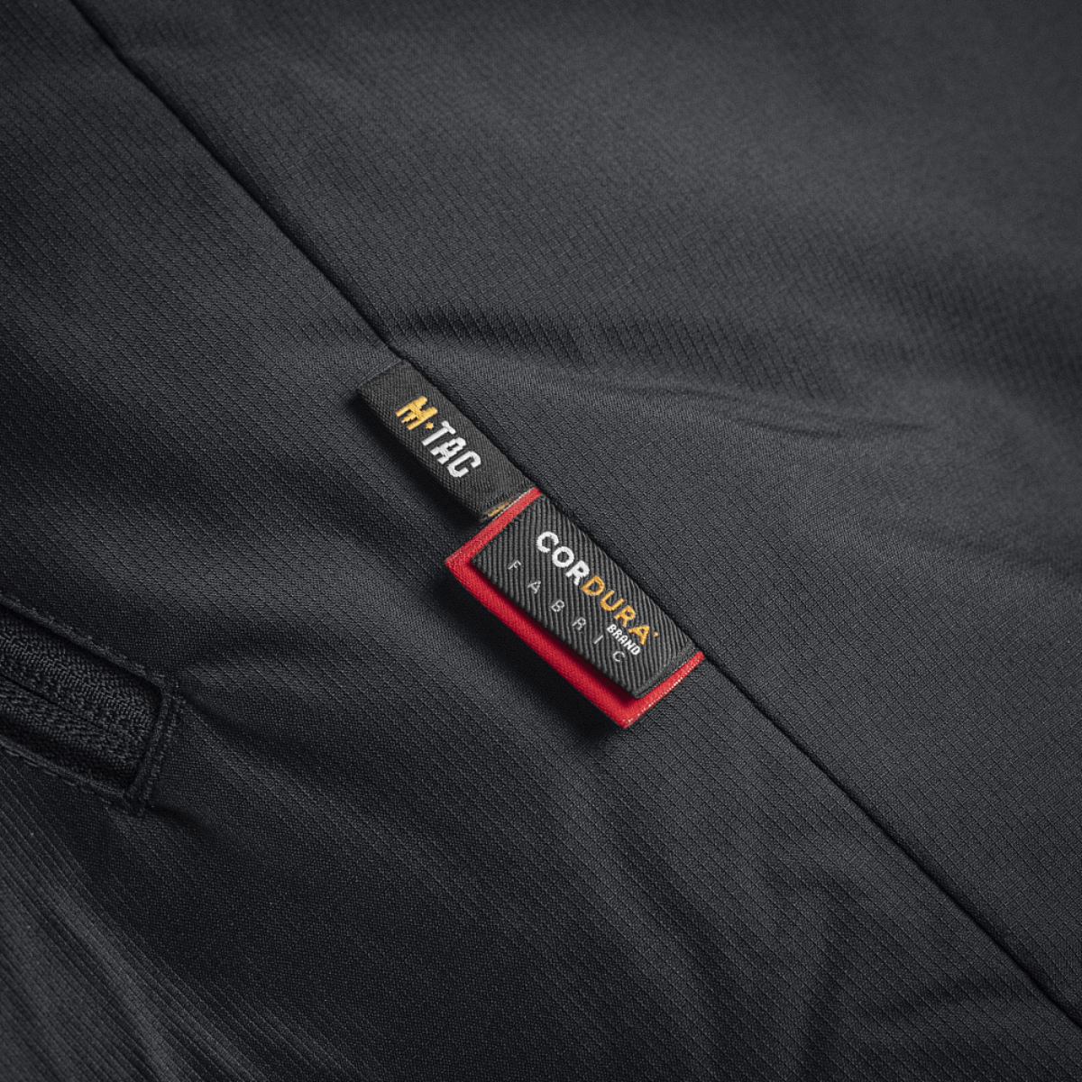 Nærbillede af M-Tac Alpha Gen.III Pro Vinterjakke med forstærket materiale og mærkeetiket.