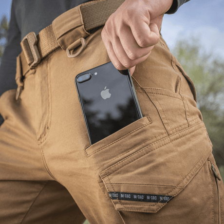 M-Tac Bukser Aggressor Vintage med mobiltelefon i lommen, viser funktionalitet og stil til hverdagsbrug og feltarbejde.