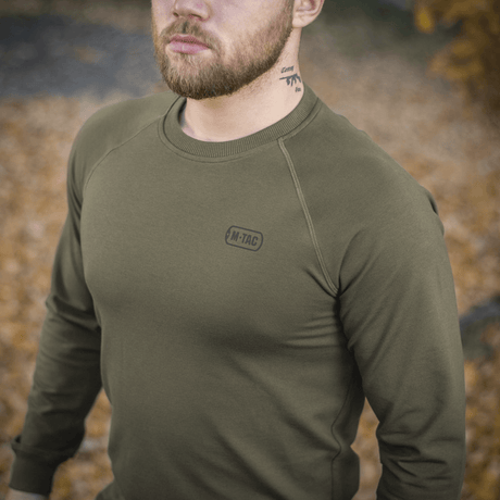 Mand iført M-Tac Raglan Athlete sweatshirt i oliven farve med rund hals og raglanærmer, perfekt til sport og hverdag