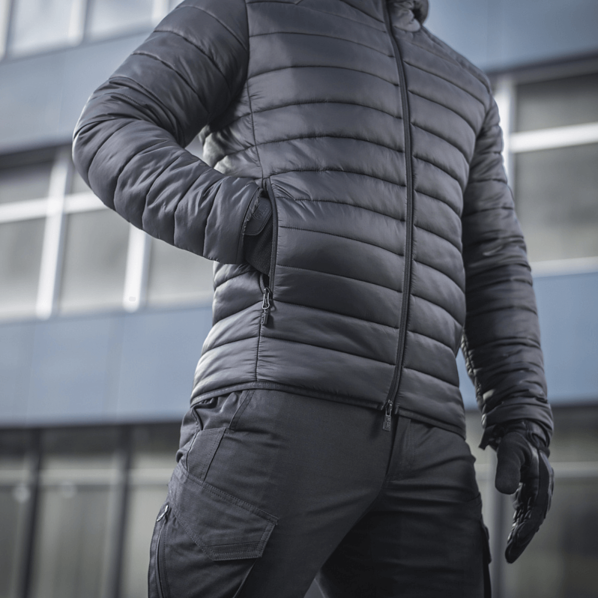 Person iført M-Tac Stalker Gen.III Jakke foran moderne bygning, viser jakkens isolering og stilfulde design.