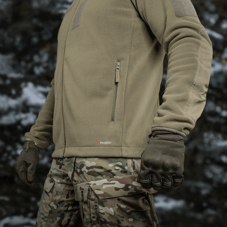 M-Tac Combat Fleece Polartec Jakke i taktisk brug med camo-bukser, viser varme og funktionalitet, perfekt til udendørsaktiviteter.