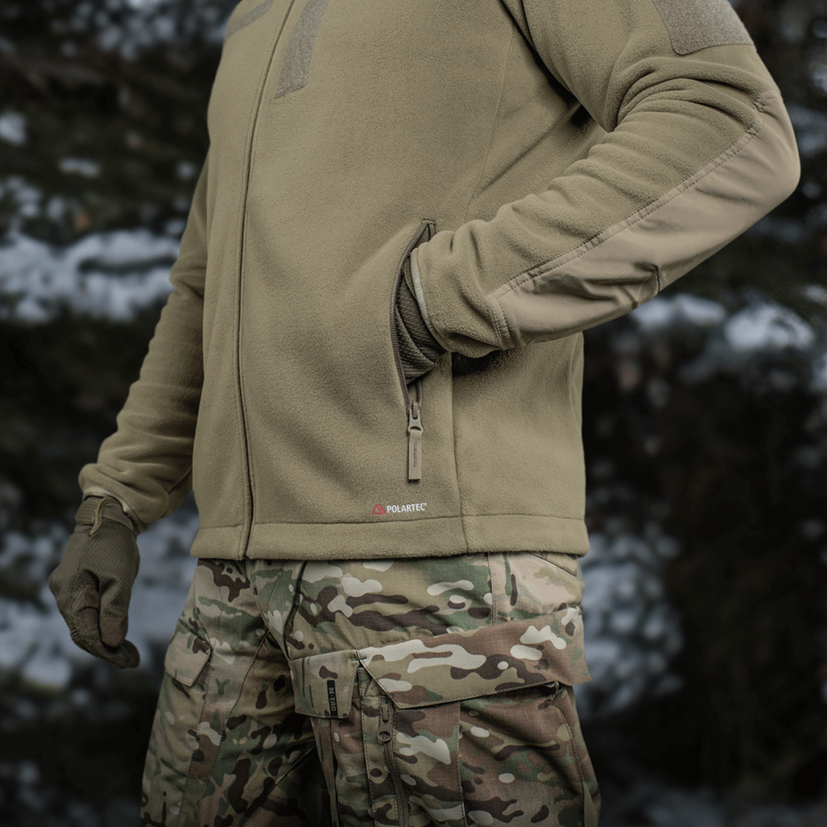 M-Tac Combat Fleece Polartec Jakke med YKK lynlåse og Velcro-paneler til taktisk brug, vist på person i skovmiljø.