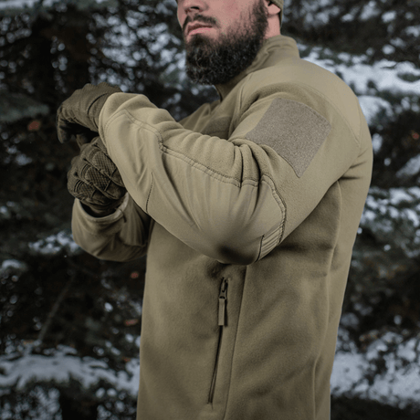 Mand iført M-Tac Combat Fleece Polartec Jakke i skovmiljø, viser jakke detaljer, perfekt til taktisk eller casual brug.