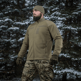 Mand iført M-Tac Combat Fleece Polartec Jakke i skovmiljø, viser jakkeens varme og funktionelle design.