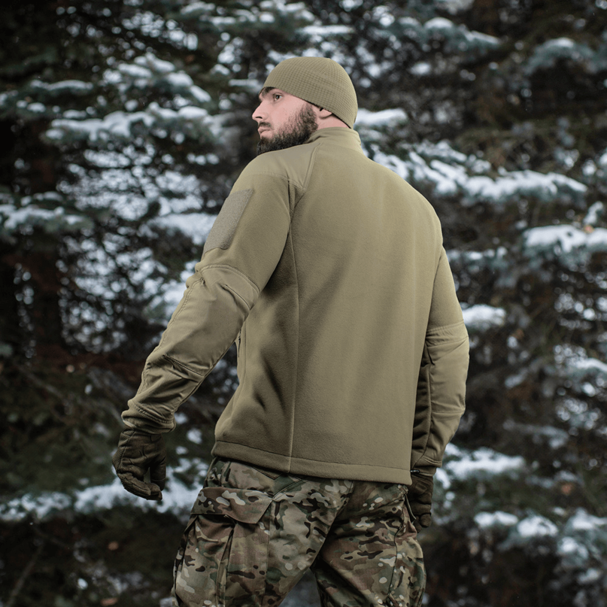 Mand iført M-Tac Combat Fleece Polartec Jakke i skovmiljø, viser funktionelt design og materialer. Perfekt til taktisk brug.
