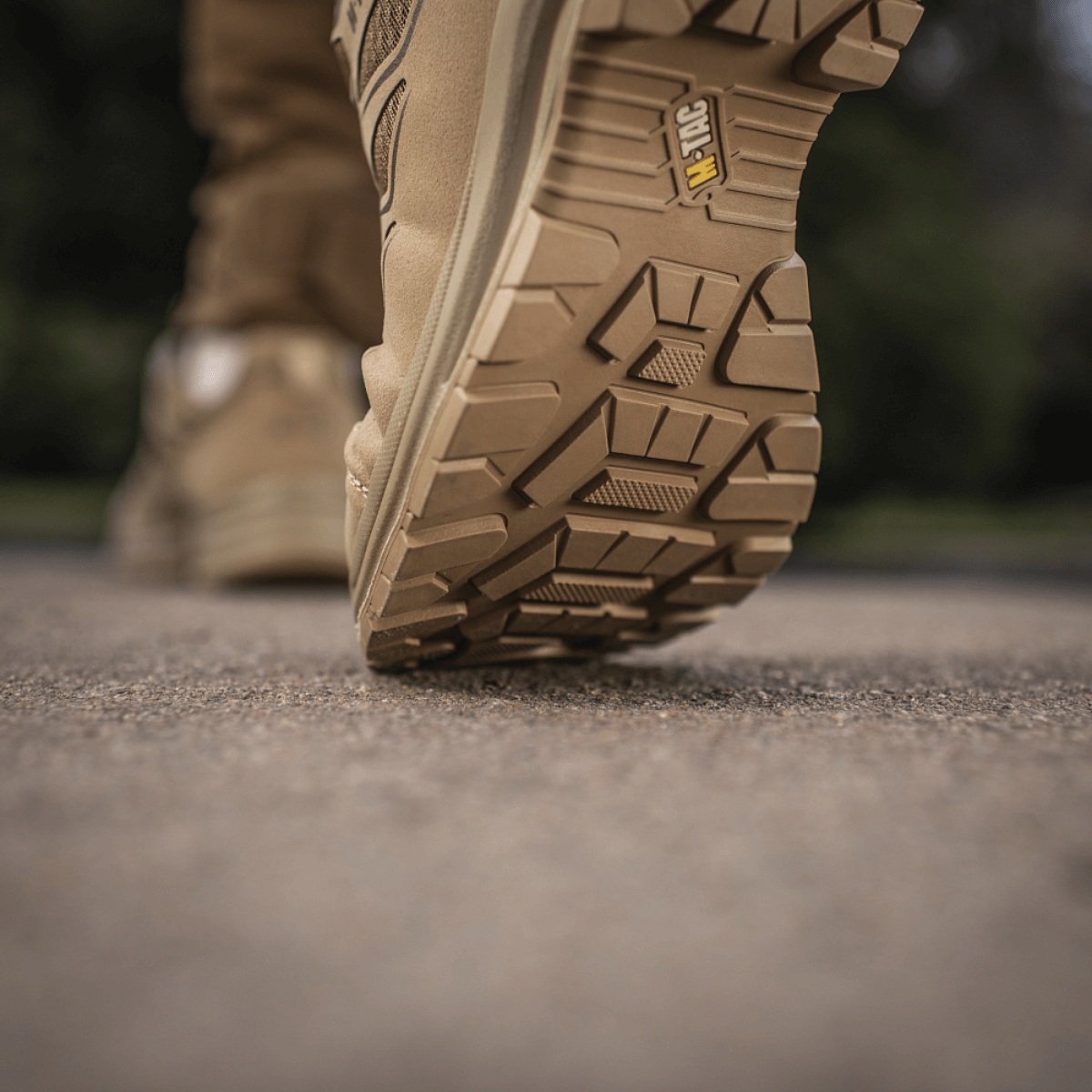 M-Tac Tactical Sneakers IVA i aktion på et udendørs underlag, viser den robuste sål ideel til trekking og outdoor-aktiviteter.