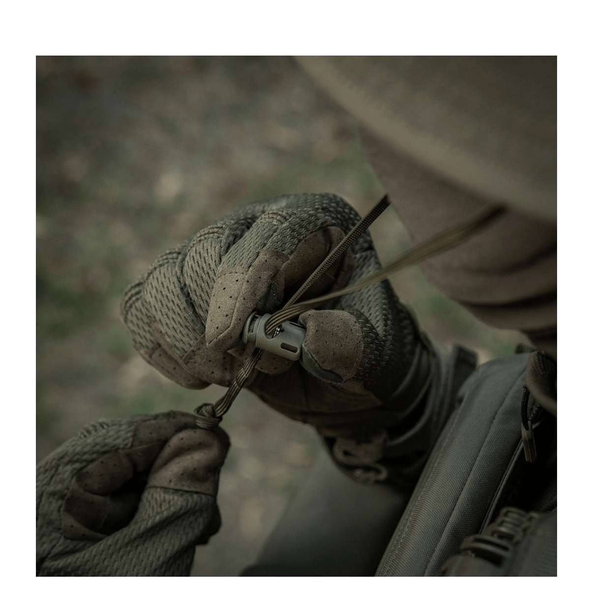 Person iført M-Tac Panamahat Gen. II Summer Flex justerer snoretræk med handsker på.