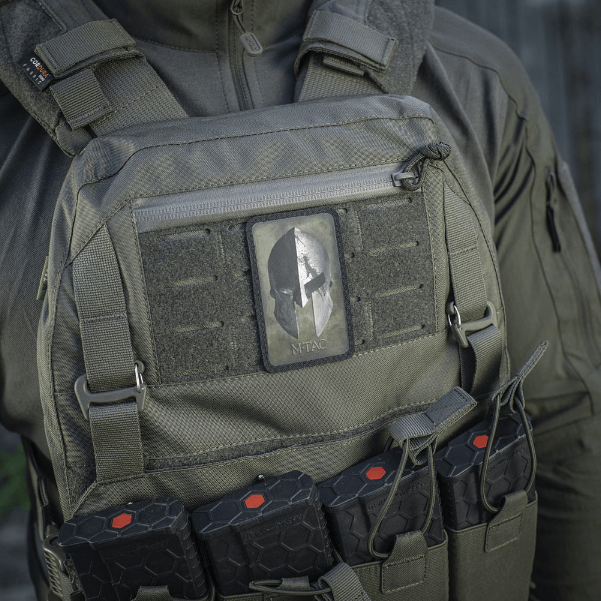 M-Tac Spartan Hjelm Patch på taktisk vest, symboliserer mod og styrke, lavet af slidstærk Cordura 500D, ideel til militært udstyr.