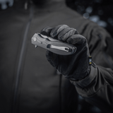 Person holding M-Tac Outdoor & Militær foldekniv - Type 6 with black G10 composite handle in gloved hand