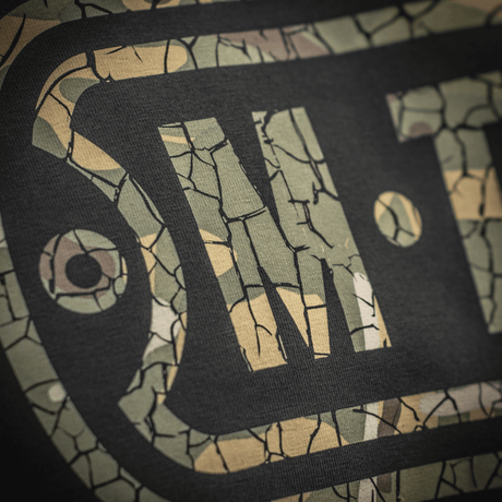 M-Tac T-Shirt Logo med camouflage mønster og ikonisk logo nærbillede, viser stil og kvalitet, slogan på ærme og rygdetaljer.