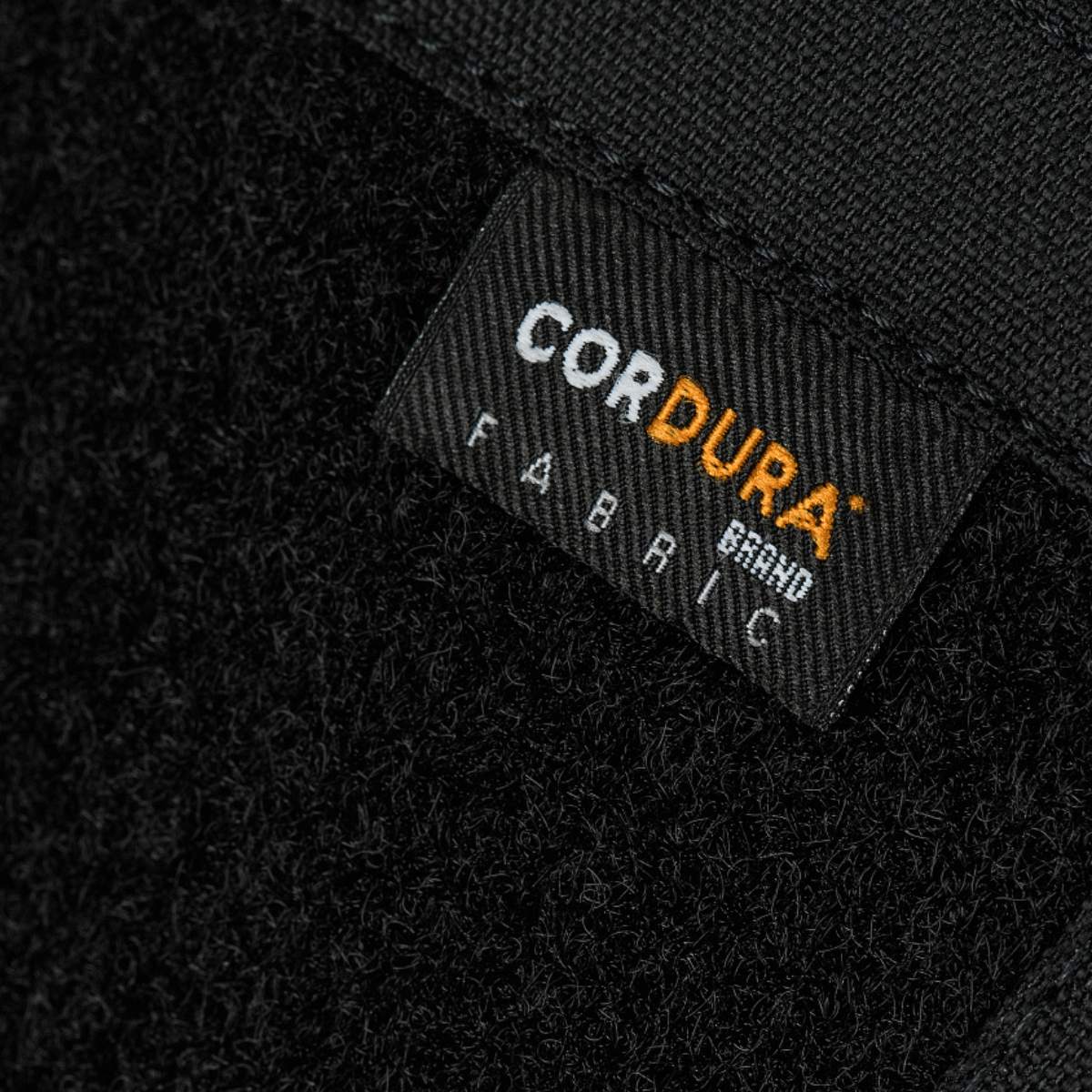 Nærbillede af Cordura stofmærke på M-Tac Sphaera Hardsling Bag Large Elite med Velcro, fremstillet af holdbare materialer.