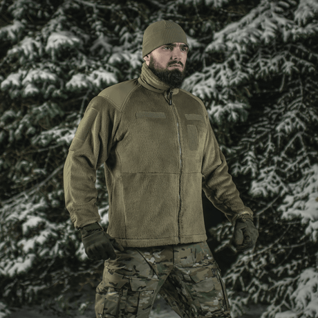 Mand i skov bærer M-Tac Battle Fleece Polartec Jakke, perfekt til militær og politi, fremhæver komfort og holdbarhed i vinterlandskab.