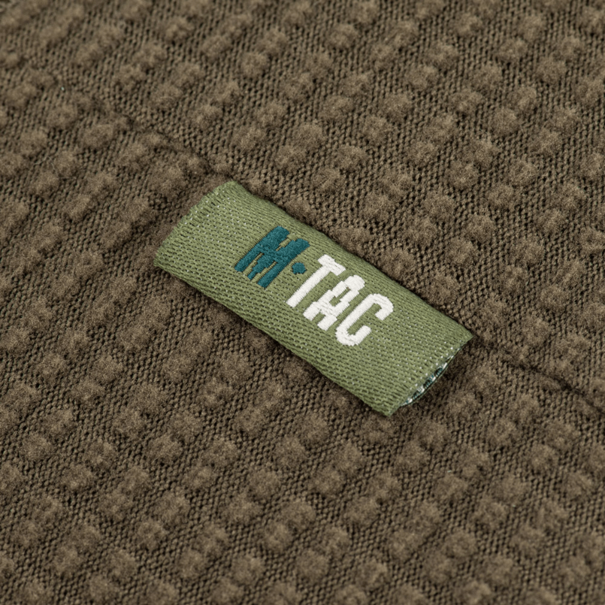 M-Tac Hjelm Watch Cap Polartec - tæt på tekstilstruktur med M-Tac-logo, ideel til koldt vejr og komfort under hjelme.