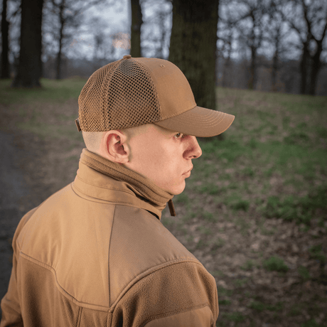Mand bærer M-Tac Mesh Flex Ripstop Baseball Cap i skovmiljø, der viser kasketens mesh-paneler og holdbare skygge.