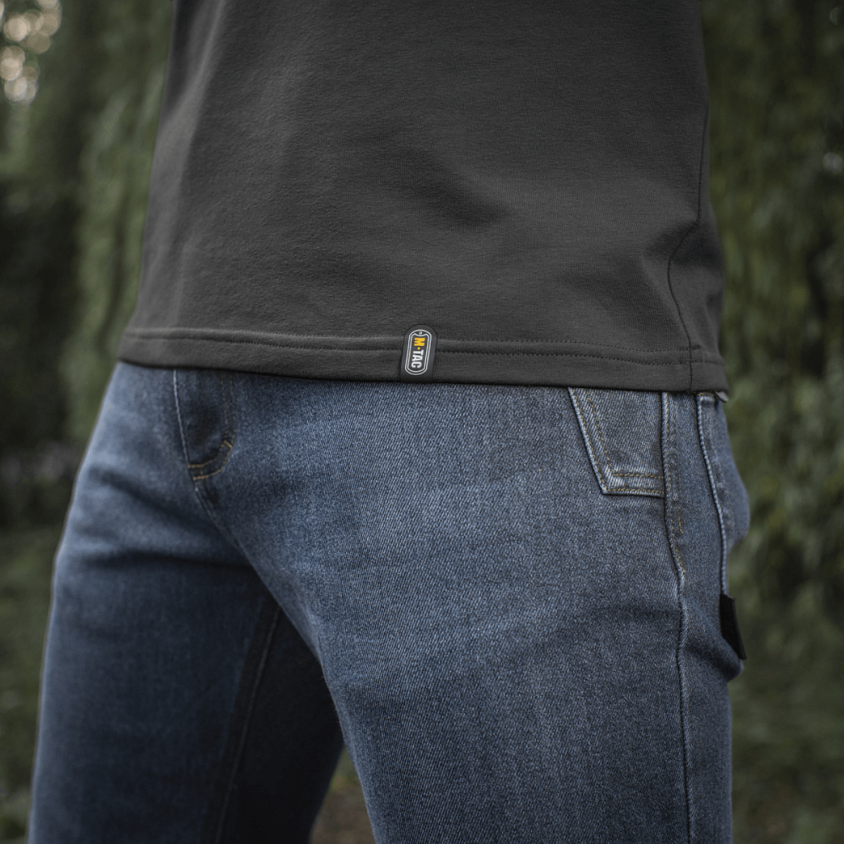 M-Tac Raglan T-Shirt 93/7 i tæt op med denim jeans, fremhæver åndbarhed og bevægelsesfrihed i naturen.