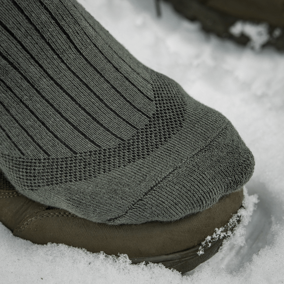 M-Tac Sokker Mid Calf Mk.4 til mænd, i brug under trekking i sne, med polstrede områder for beskyttelse og støtte.