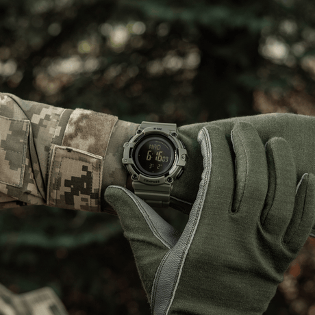 M-Tac Tactical Ur med Kompas 2233 båret af soldat udendørs, viser robust design og funktioner som LED-belysning og 5ATM vandmodstand.