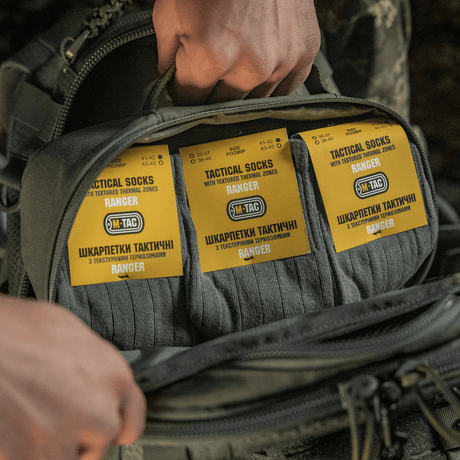 M-Tac Taktiske Sokker Ranger pakket i en rygsæk, ideel til komfort og aktiviteter udendørs, med elastisk kant og anatomisk pasform.