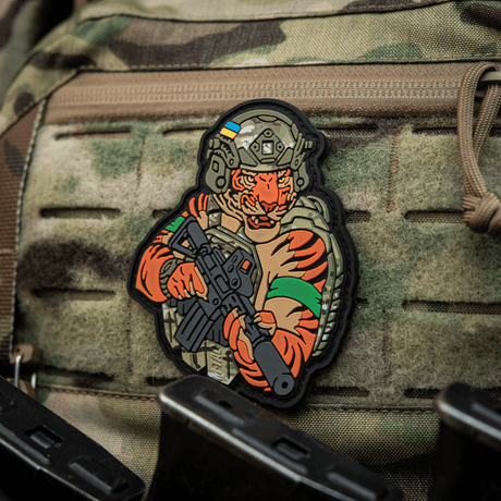 Alt tag: M-Tac Patch Tiger Green Tape PVC - 3D patch af tiger med AR-15, hjelm og QRS plate carrier på camouflageret udstyr.