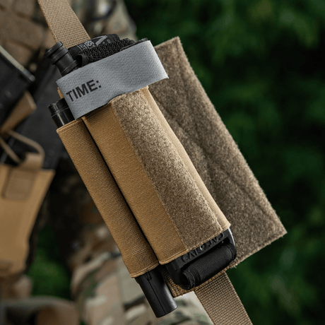 M-Tac Tourniquet Pouch Elastic Gen.5 i Cordura 500D på taktisk udstyr, viser hurtig adgang og sikker fastgørelse af tourniquet.