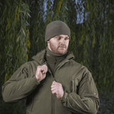 Mand iført M-Tac Fleece Polartec Watch Cap i skovmiljø, ideel til udendørs vinteraktiviteter og beskyttelse mod kulde og vind.