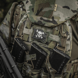 M-Tac Patch Jolly Roger PVC fastgjort på taktisk rygsæk med camouflage-mønster, symboliserer eventyrlyst og beslutsomhed.