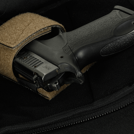 Nærbillede af en pistol i en M-Tac Sphaera Hardsling Bag Large Elite med Velcro, lavet af robust Cordura stof med velcro fastgørelse.