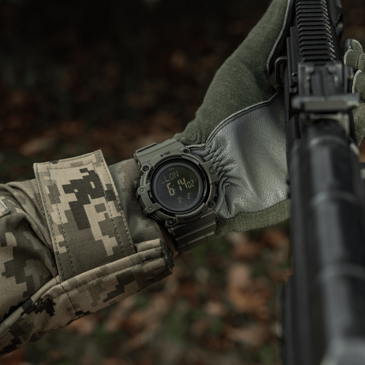 M-Tac Tactical Ur med Kompas 2233 båret af soldat i skov, viser funktionalitet for outdoor og taktisk brug, med holdbart design og kompas.