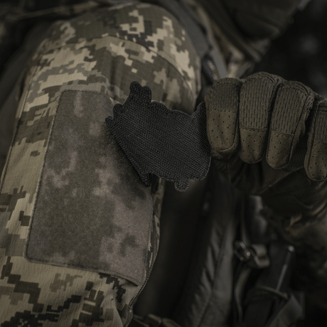 Soldat i camouflagejakke fastgør M‑Tac Patch Baba-Yaga Vertical på ærme med velcro.