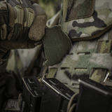 En soldat justerer en M-Tac Patch Jolly Roger PVC på sin camouflage-vest under taktisk træning udendørs.